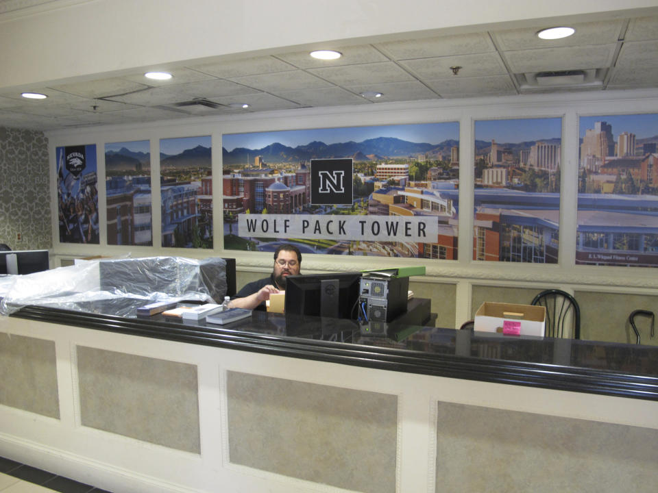 In this Monday, Aug. 19, 2019 photo, a University of Nevada, Reno, employee oversees the desk in the lobby of a Circus Circus casino hotel tower in downtown Reno, Nev., that has been converted into a dormitory a half-mile from the main campus. Now called Wolf Pack Tower, it will house about 1,300 UNR students for the coming school year after a July gas explosion shut down the two largest dorms. (AP Photo/Scott Sonner)