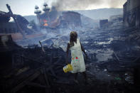 <p>A woman walks near a fire at the Hyppolite iron market in downtown Port-au-Prince, Haiti, Jan. 29, 2010. (Photo: Jorge Silva/Reuters) </p>