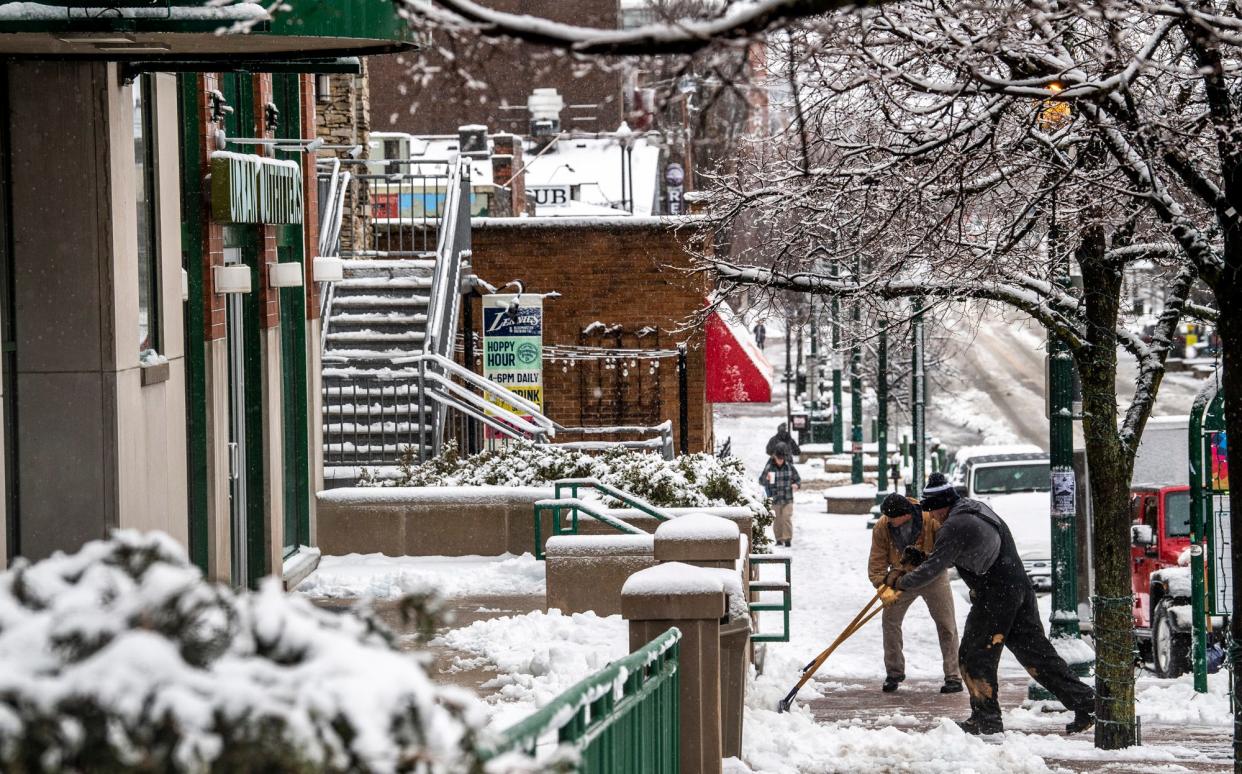 People shovel sidewalks along Kirkwood Avenue near the Indiana University campus on Wednesday, Jan. 25, 2023.