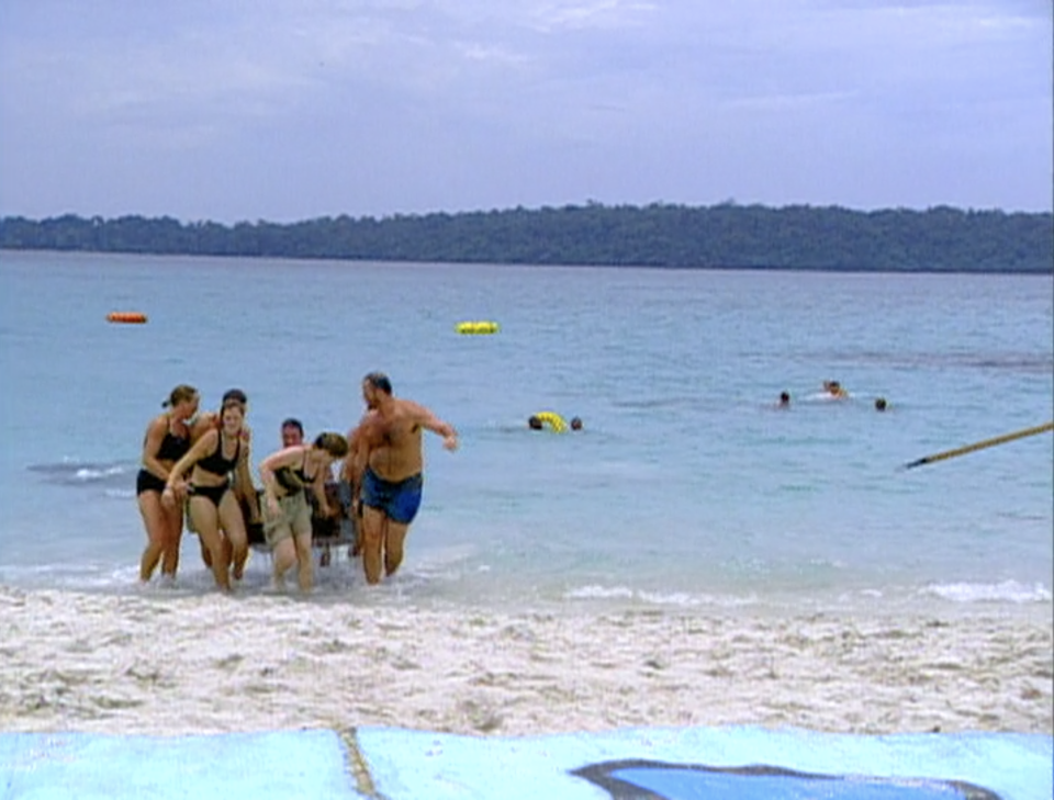 A tribe carries a large crate out of the water in an immunity challenge in Survivor: Borneo