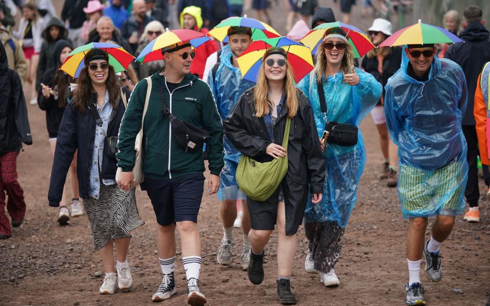 Rainbows all round: festival goers come prepared with umbrella hats - PA