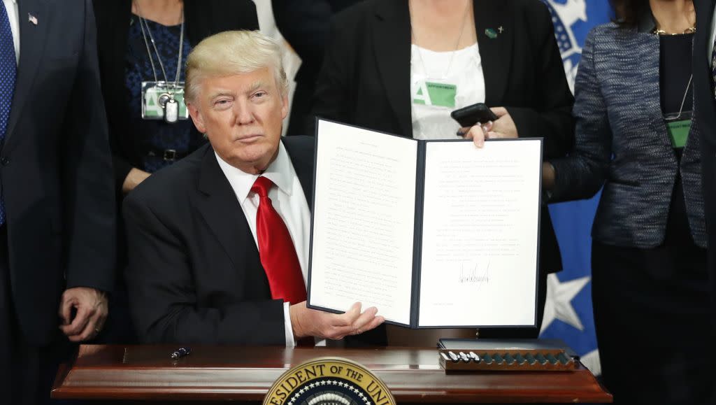 US president Donald Trump holds up an executive order to build a border wall with Mexico.
