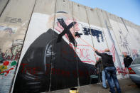 <p>A Palestinian man crosses out a mural depicting U.S. President Donald Trump that is painted on a part of the Israeli barrier, in the West Bank city of Bethlehem Dec. 7, 2017. (Photo: Mussa Qawasma/Reuters) </p>