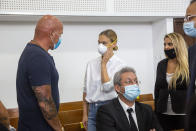 Israeli top model Bar Refaeli, center, wearing a face mask arrives to a court along with her father, Raffi, left, and lawyers, in Tel Aviv, Israel, Monday, July 20, 2020. Refaeli signed a plea bargain agreement with authorities to settle a long-standing tax evasion case against her and her family. The deal will require Refaeli to serve nine months of community service while her mother, Zipi, will be sent to prison for 16 months. The two are also ordered to pay a $1.5 million fine on top of millions of back taxes owed to the state. (AP Photo/Oded Balilty, Pool)