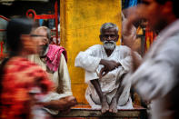 A man looks straight at the camera as pedestrians pass him by. The image was taken by Monika Mukherjee (Monika Mukherjee)