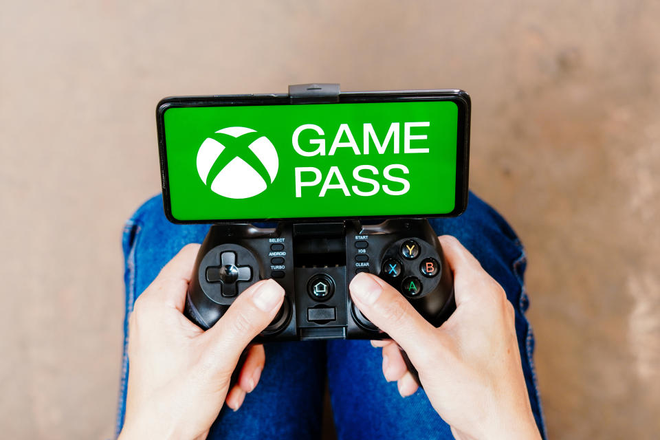 BRAZIL - 2023/08/08: In this photo illustration, a person playing on a joystick and the Xbox Game Pass logo displayed on a smartphone screen. (Photo Illustration by Rafael Henrique/SOPA Images/LightRocket via Getty Images)