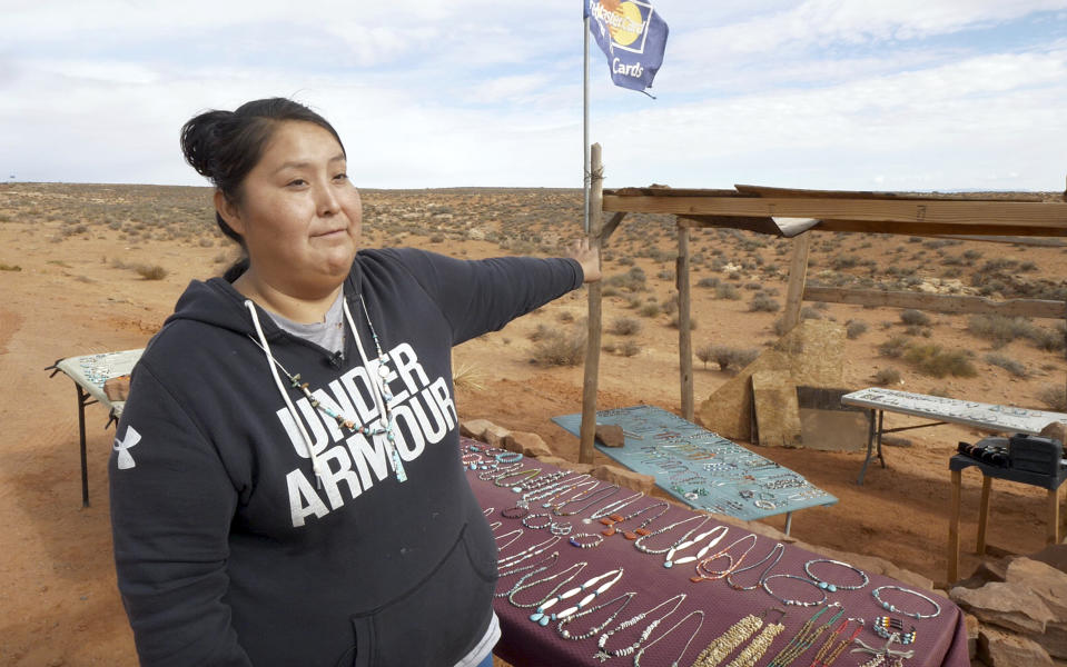 In this Thursday, Oct. 25, 2018, photo, Tammie Nakai displays her jewelry at her stand in Monument Valley, Utah, where tourists stand the highway to recreate a famous running scene from the movie "Forest Gump.". As Native American tribes around the country fight for increased access to the ballot box, Navajo voters in one Utah county could tip the balance of power in the first general election since a federal judge ordered overturned their voting districts as illegally drawn to minimize native voices. (AP Photo/Rick Bowmer)