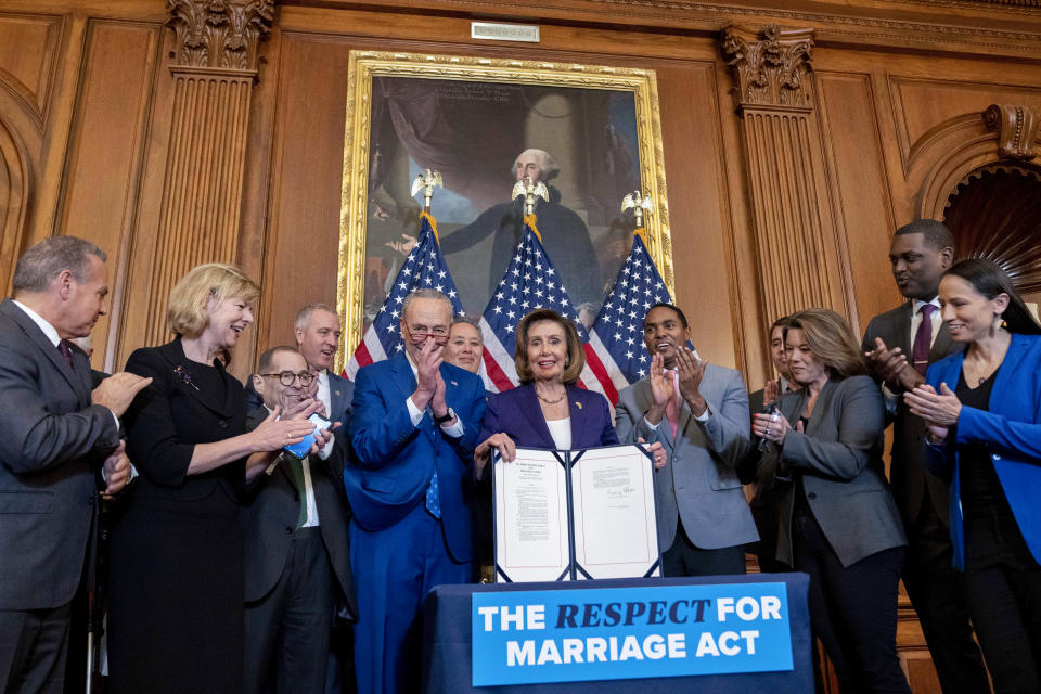 FILE - House Speaker Nancy Pelosi of Calif., accompanied by Senate Majority Leader Sen. Chuck Schumer of N.Y., center left, and other members of congress, signs the H.R. 8404, the Respect For Marriage Act, on Capitol Hill in Washington, Dec. 8, 2022. (AP Photo/Andrew Harnik, File)