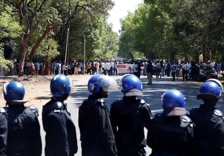 Riot poilce stand before striking healthcare workers protesting over the disappearance of Peter Magombeyi, the leader of their union, outside a hospital in Harare