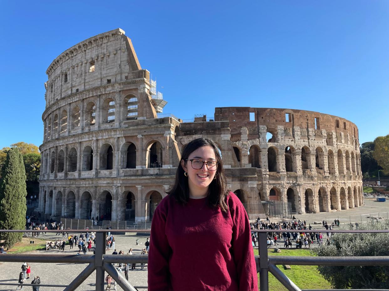 hannah posing for a photo with the colosseum in the background in rome, italy