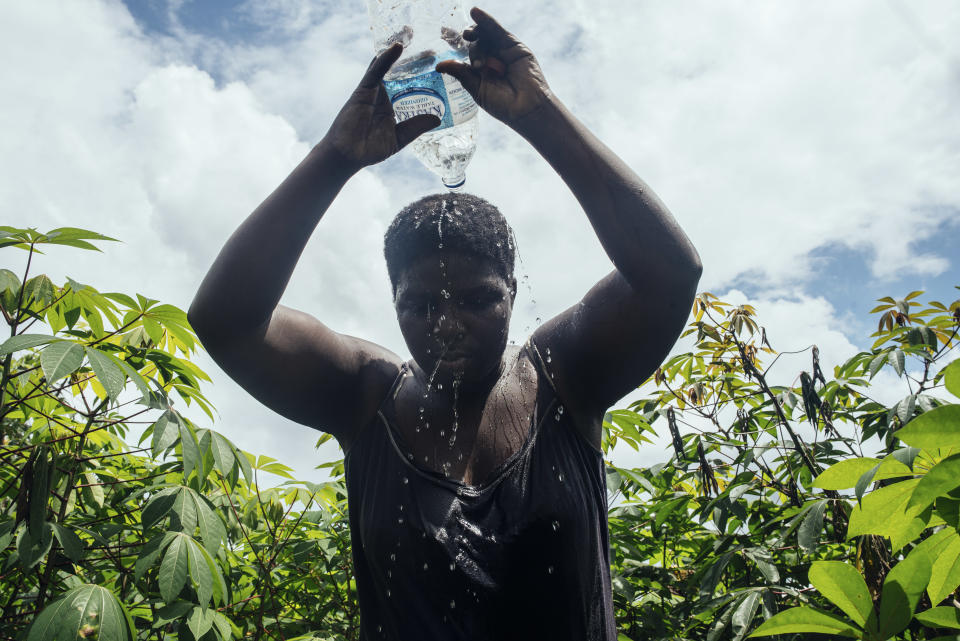 Faith Osi se vierte agua en la cabeza para refrescarse mientras trabaja en la granja de yuca de su familia en Obrikom, Nigeria, el 21 de julio de 2020. (KC Nwakalor/The New York Times)