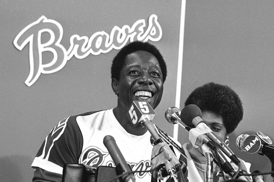 FILE - Atlanta Braves' Hank Aaron smiles during a press conference at Atlanta Stadium, Ga., after the game in which he hit his 715th career home, in this April 8, 1974, file photo. With him is his wife Billye, partially obscured. Hank Aaron, who endured racist threats with stoic dignity during his pursuit of Babe Ruth’s home run record and gracefully left his mark as one of baseball’s greatest all-around players, died Friday. He was 86. The Atlanta Braves, Aaron's longtime team, said he died peacefully in his sleep. No cause was given. (AP Photo/File)