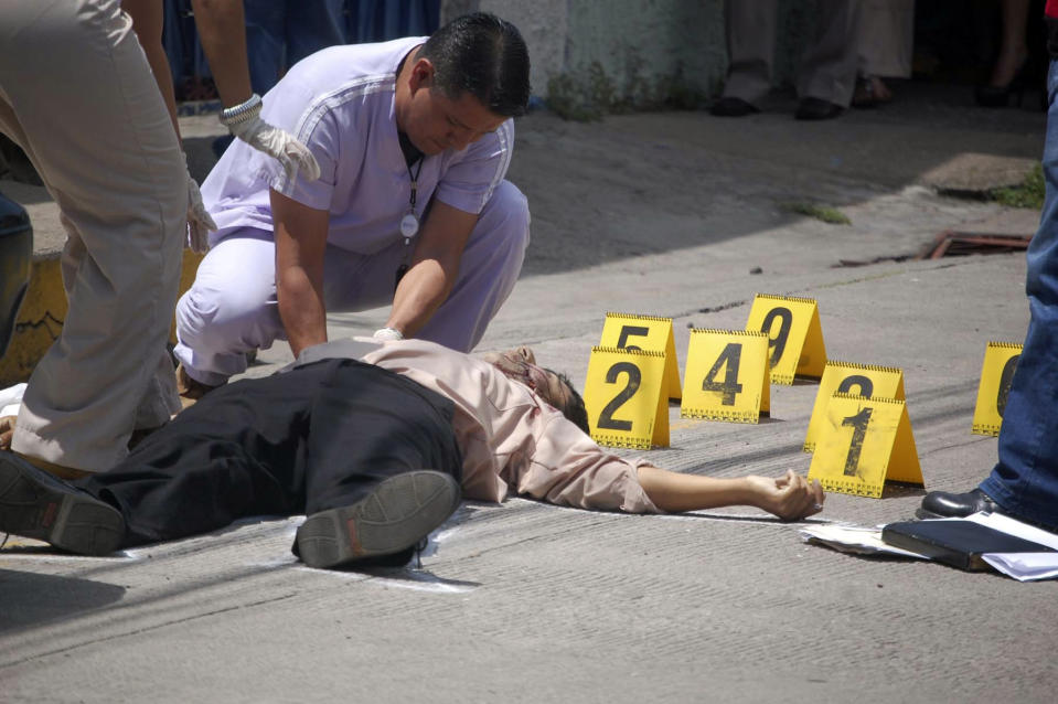 Forensic workers examine the body of human rights District Attorney Manuel Eduardo Díaz Mazariegos after he was gunned down in Choluteca, Honduras, Monday Sept. 24, 2012. A day earlier, Antonio Trejo Cabrera, a prominent Honduran human rights lawyer was also gunned down in the capital city of Tegucigalpa. (AP Photo)