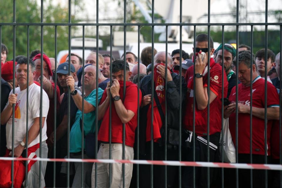 Liverpool fans cover their mouths and noses as they queue to gain entry to the stadium (Peter Byrne/PA) (PA Wire)