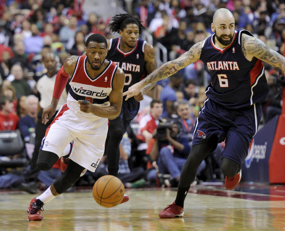 Washington Wizards guard John Wall (2) chases the ball against Atlanta Hawks center Pero Antic (6), of Macedonia, and Cartier Martin, center, during the second half of an NBA basketball game, Saturday, March 29, 2014, in Washington. The Wizards won 101-97. (AP Photo/Nick Wass)