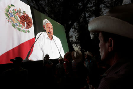 People watch Mexico's President Andres Manuel Lopez Obrador on a video screen during an event in Badiraguato, in the Mexican state of Sinaloa, Mexico February 15, 2019. REUTERS/Daniel Becerril