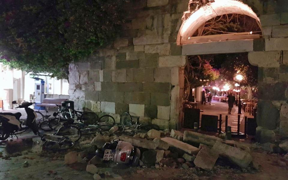 People walk near a damaged building after an strong earthquake on the Greek island of Kos - Credit: AP