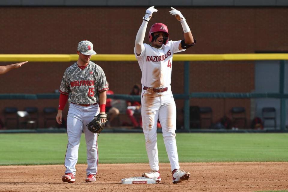 Arkansas baserunner Jalen Battles (4) celebrates in front of North Carolina State infielder J.T. Jarrett (15) after reaching second base in the second inning of an NCAA college baseball super regional game Friday, June 11, 2021, in Fayetteville, Ark. (AP Photo/Michael Woods)