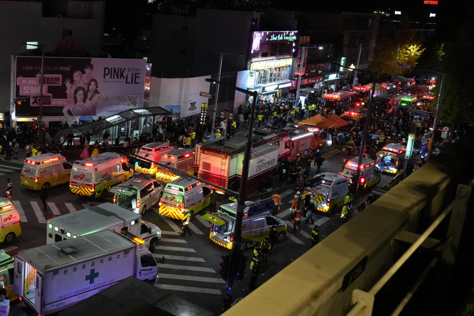 Ambulances and rescue workers arrive at the street near the scene of a crowd surge in Seoul, South Korea, Sunday, Oct. 30, 2022. Witnesses say the nightmarish scene intensified as people performed CPR on the dying and carried limp bodies to ambulances, while dance music pulsed from garish clubs lit in bright neon. Others tried desperately to pull out those who were trapped underneath the crush of people, but failed because too many in the crowd had fallen on top of them. (AP Photo/Lee Jin-man)