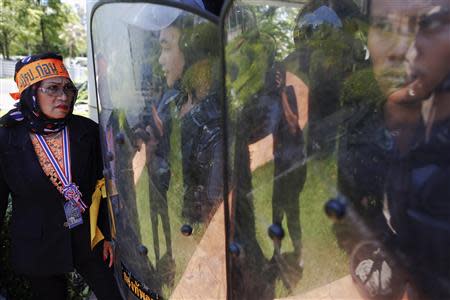 An anti-government protester stands in front of Air Force military personnel holding shields, after protesters broke into the grounds of an air force compound in Bangkok May 15, 2014. REUTERS/Damir Sagolj