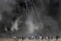 <p>Palestinian protesters gather in front of burned tires while Israeli soldiers fire teargas during clashes with Israeli troops along Gaza’s border with Israel, east of Khan Younis, Gaza Strip, Friday, April 6, 2018. (Photo: Adel Hana/AP) </p>