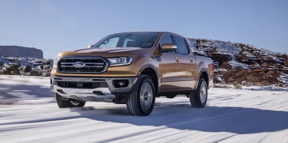 An orange 2019 Ford Ranger, a midsize pickup truck, on a snowy country road.