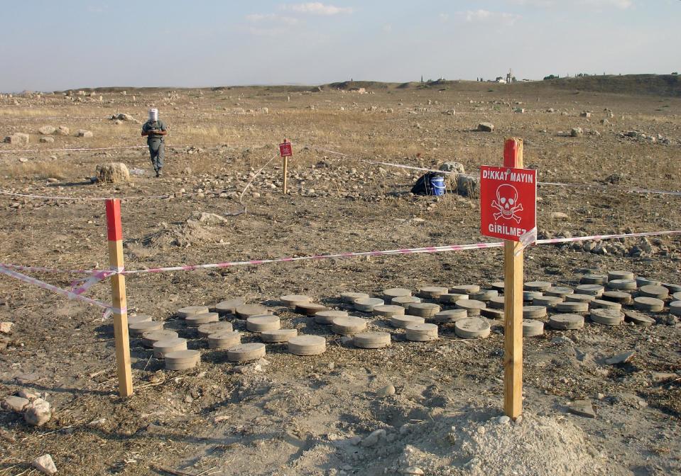 FILE - In this June 17, 2010 file photo, a land mine expert works in mined land in the Karkemish archaeological site at the Turkey-Syria border in Gaziantep province, Turkey. Starting in the 1950s, Turkish forces planted more than 600,000 U.S.-made "toe poppers" _ mines designed to maim, not kill _ and other land mines along much of its 900-kilometer (560-mile) border with Syria, which runs from the Mediterranean Sea to Iraq. The aim was to stop smugglers whose cheap black market goods undercut the Turkish economy and later to thwart Kurdish rebels from infiltrating Turkey's southeast. (AP Photo/File)