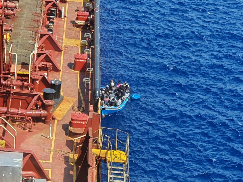 Migrants sit in a boat alongside the Maersk Etienne tanker off the coast of Malta