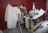 A worker from the Unidos de Padre Miguel samba school shows a medical scrub she is making, during the new coronavirus pandemic in Rio de Janeiro, Brazil, Tuesday, April 7, 2020. Samba schools that a spend all year making Carnival costumes have turned their sewing machines to a different purpose, making scrubs and face masks for medical workers. (AP Photo/Silvia Izquierdo)