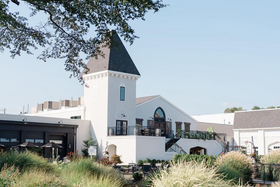 A white winery surrounded by greenery.