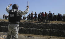 Central American migrants approach a Mexican National Guard after crossing the Suchiate River from Guatemala to Mexico near Ciudad Hidalgo, Mexico, Monday, Jan. 20, 2020. More than a thousand Central American migrants hoping to reach the United States marooned in Guatemala are walking en masse across a river leading to Mexico in an attempt to convince authorities there to allow them passage through the country.(AP Photo/Marco Ugarte)