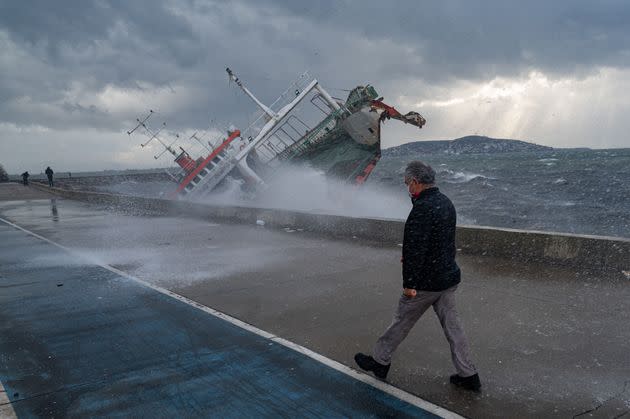 A man walks near a boat that has capsized due to strong winds in Istanbul, on Tuesday. Four people were killed and dozens injured as the city was hit by high winds on Monday. (Photo: YASIN AKGUL/AFP via Getty Images)