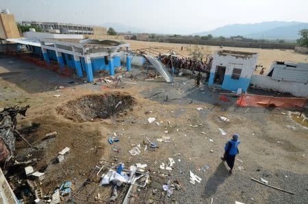 People look at a crater caused by a Saudi-led coalition air strike at the yard of a hospital operated by Medecins Sans Frontieres in the Abs district of Hajja province, Yemen August 16, 2016. REUTERS/Abduljabbar Zeyad