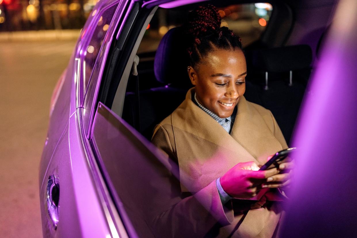 Well dressed businesswoman text messaging from the back seat of a car