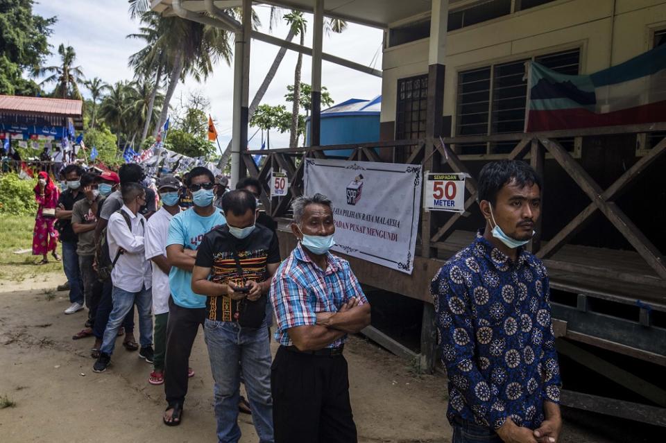 Voters wearing protective masks queue up to cast their votes during the Sabah state election in SK Pulau Gaya September 26, 2020.