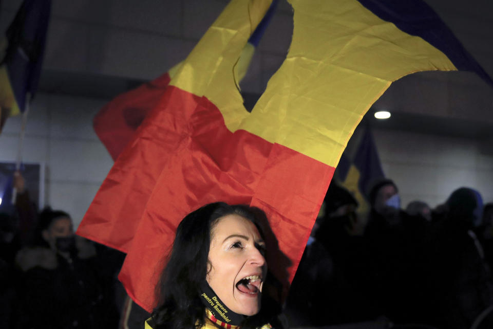 A woman shouts slogans during a protest outside the health ministry after a deadly fire at a hospital treating COVID-19 patients in Bucharest, Romania, Saturday, Jan. 30, 2021. Hundreds marched during a protest organized by the AUR alliance demanding the resignation of several top officials, after a fire early Friday at a key hospital in Bucharest that also treats COVID-19 patients killed five people. (AP Photo/Vadim Ghirda)