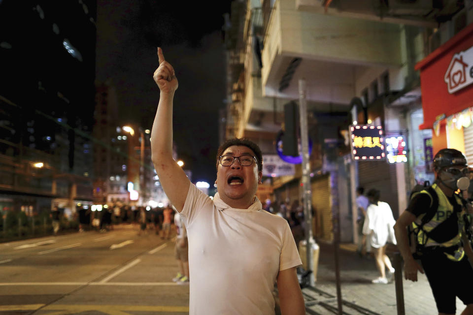 A man shouts at policemen as protesters face off with policemen in Hong Kong, Wednesday, Aug. 14, 2019. German Chancellor Angela Merkel is calling for a peaceful solution to the unrest in Hong Kong amid fears China could use force to quell pro-democracy protests. (AP Photo/Vincent Yu)