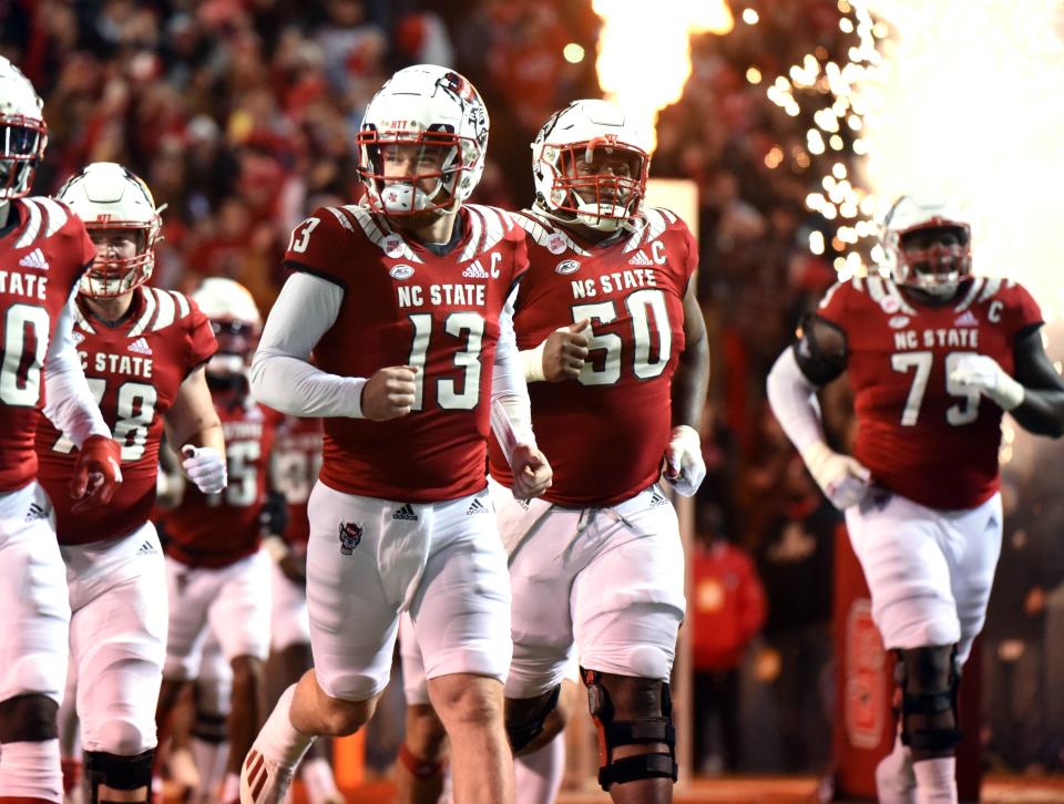 Nov 26, 2021; Raleigh, North Carolina, USA; North Carolina State Wolfpack quarterback Devin Leary (13) leads his team onto the field prior to a game against the North Carolina Tar Heels at Carter-Finley Stadium. Mandatory Credit: Rob Kinnan-USA TODAY Sports