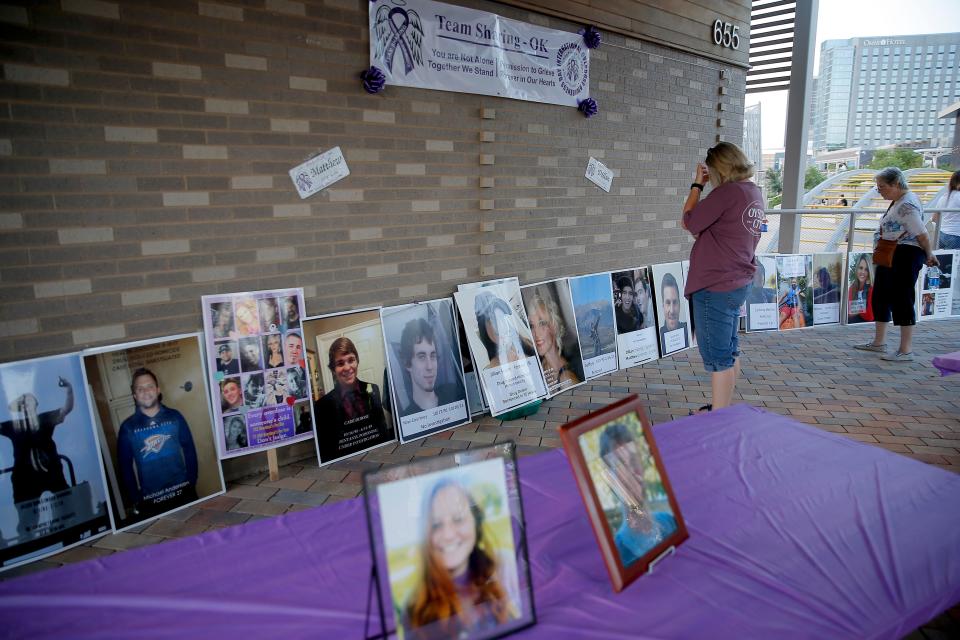 A woman looks at pictures of those who lost their lives due to an overdose before a walk organized by Team Sharing Inc. in recognition of International Overdose Awareness Day at Scissortail Park in Oklahoma City, Tuesday, Aug. 31, 2021.