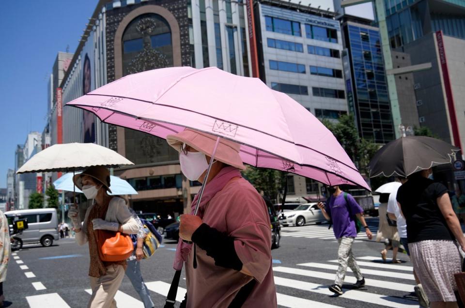 People shielding themselves from the heat in Tokyo during a heatwave in June (Franck Robichon/EPA)