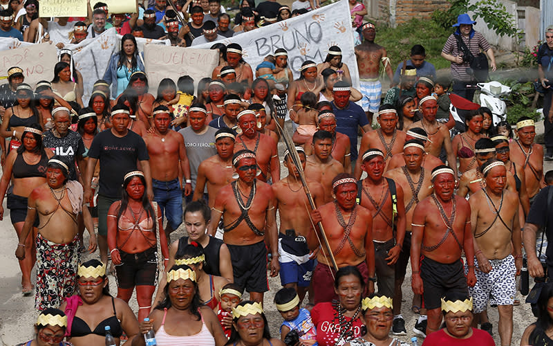 Indigenous people march to protest with some holding signs with the names of missing Indigenous expert Bruno Pereira and freelance British journalist Dom Phillips