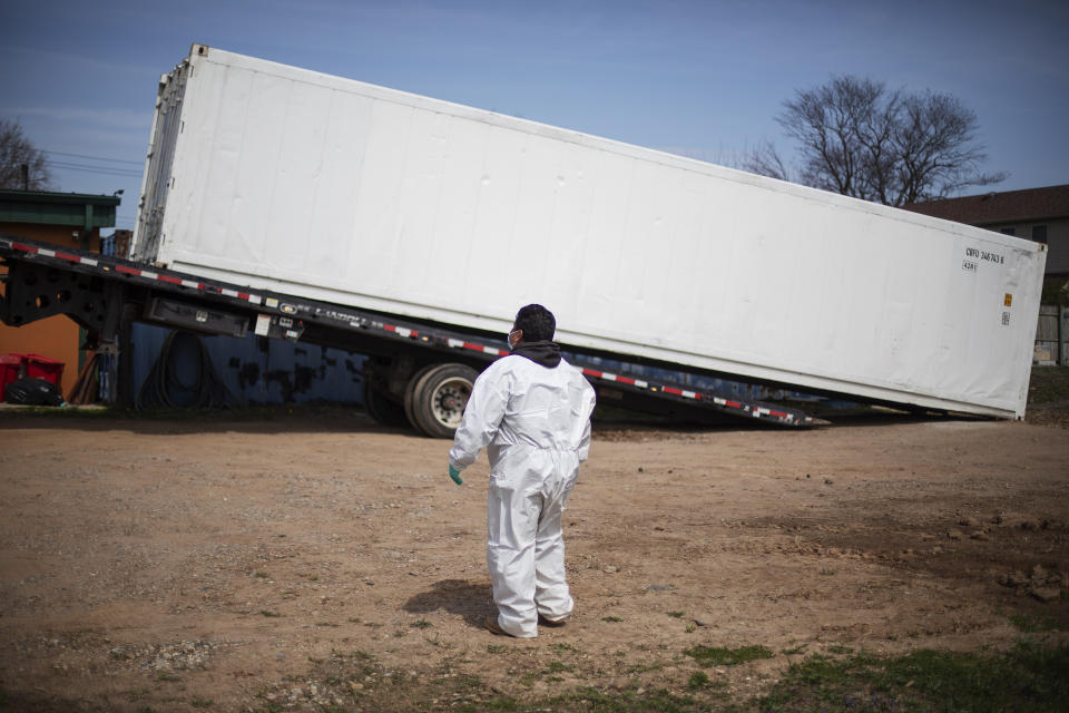 Gravedigger Thomas Cortez watches as a refrigerated trailer is delivered to keep pace with a surge of bodies arriving for burials, mostly those who died from coronavirus, at Hebrew Free Burial Association's cemetery in the Staten Island borough of New York, Tuesday, April 7, 2020. The organization stocked up on caskets before the coronavirus unleashed its worst, just as they did with protective gear for workers, garments for the dead and other supplies. They think they have enough. Then again, they thought the mortuary cooler they ordered a month ago to fit an extra four bodies would be enough extra space. Now they have a refrigerated trailer big enough to hold 20. (AP Photo/David Goldman)