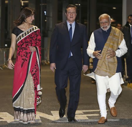 India's Prime Minister Narendra Modi (R) walks with Britain's Prime Minister David Cameron (C) and his wife Samantha in a backstage area during a welcome rally for Modi at Wembley Stadium in London November 13, 2015. REUTERS/Justin Tallis/Pool