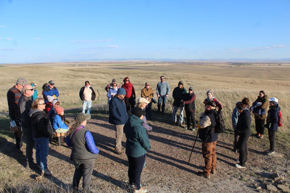 A group of 25 hikers takes in the history and cultural significance of First People's Buffalo Jump State Park as presented by Park Ranger Andy Keller