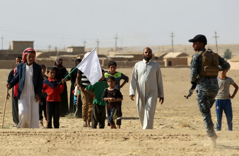 Displaced Iraqis from the Bajwaniyah village, south of Mosul, who fled fighting in the Mosul area carry a white flag as they approach security forces on October 18, 2016