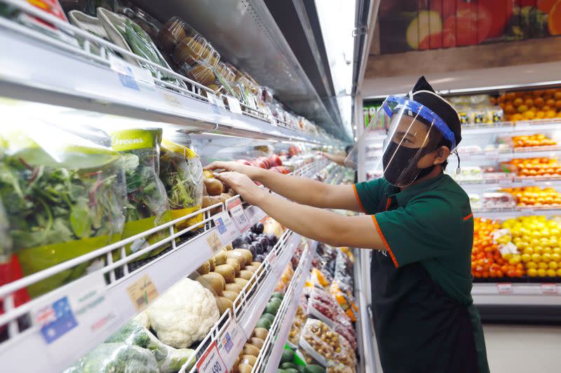 FILE PHOTO: A worker wearing a face shield and a protective face mask checks the vegetables at a Food Hall Supermarket amid the outbreak of the coronavirus disease (COVID-19), in Jakarta