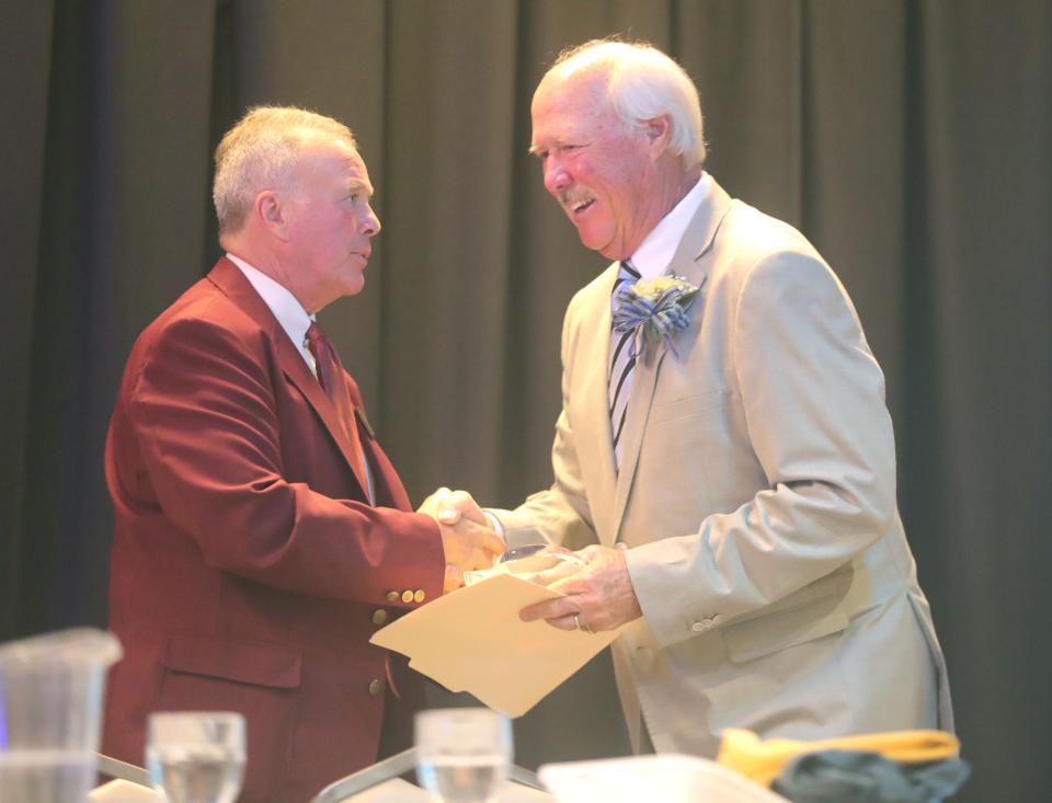 Jeff Sheeks, a board member of the Summit County Sports Hall of Fame, shakes hands with Chuck Vrabel, father of NFL coach Mike Vrabel, during the awards banquet Tuesday at Annunciation Greek Orthodox Church in Akron.