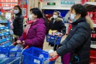 People wear face masks as they line up at the checkout in a supermarket in Beijing