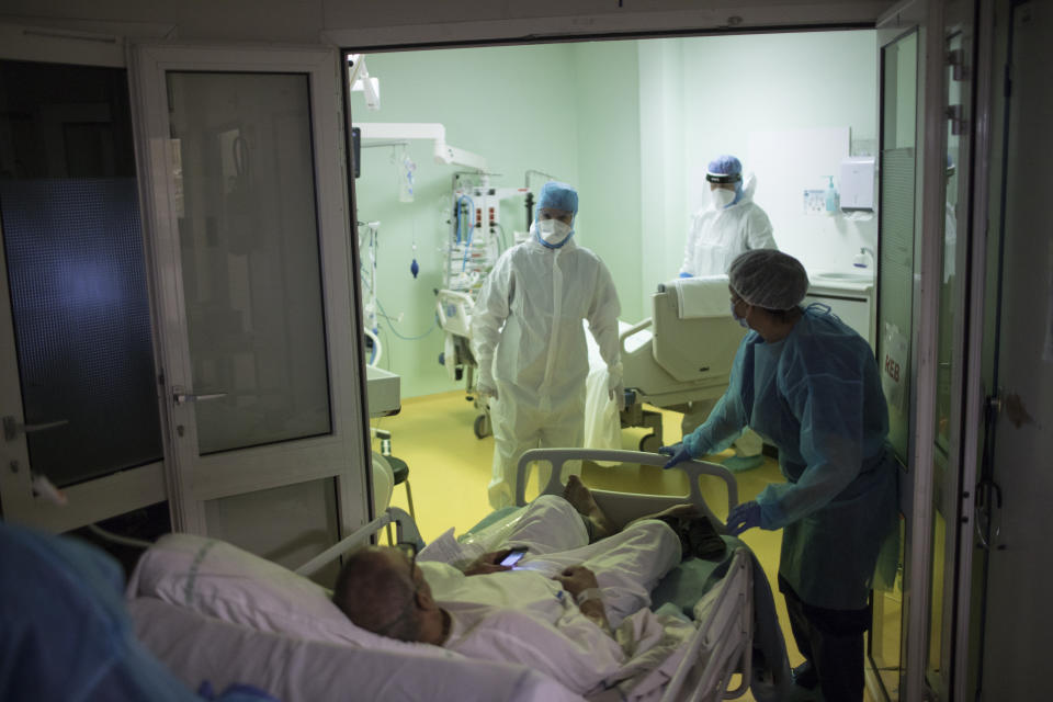 A medical crew receive a COVID-19 patient into the intensive care unit at the Joseph Imbert Hospital Center in Arles, southern France, Wednesday, Oct. 28, 2020. Many French doctors are urging a new nationwide lockdown, noting that 58% of the country's intensive care units are now occupied by COVID patients and medical staff are under increasing strain. (AP Photo/Daniel Cole)