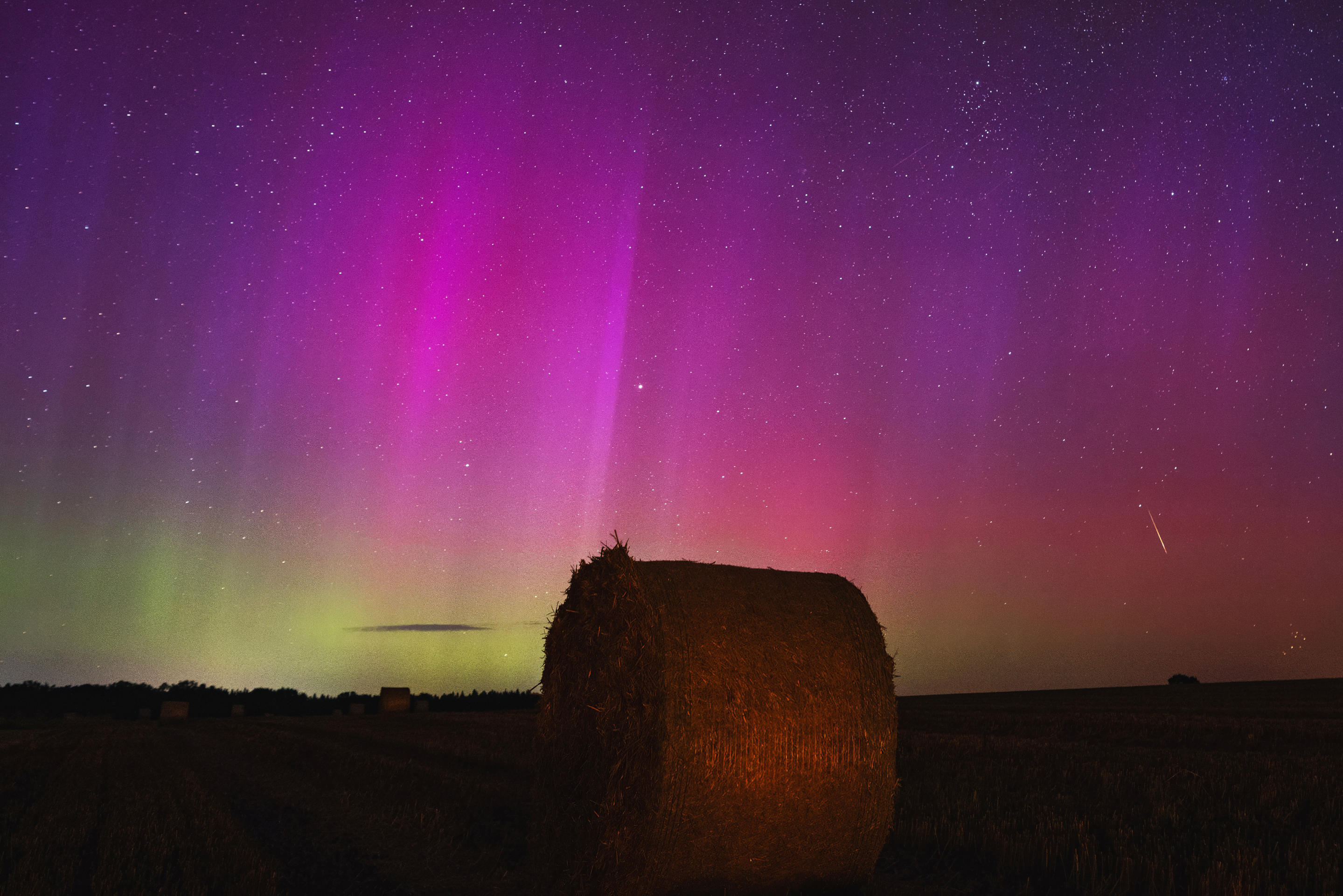 O afișare uluitoare a aurora boreală deasupra unui câmp de fân din Brandenburg, Germania.